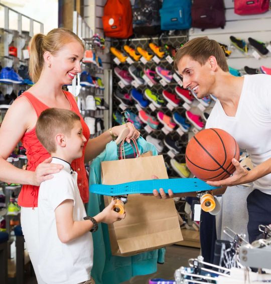 Family of three choosing skateboard in store